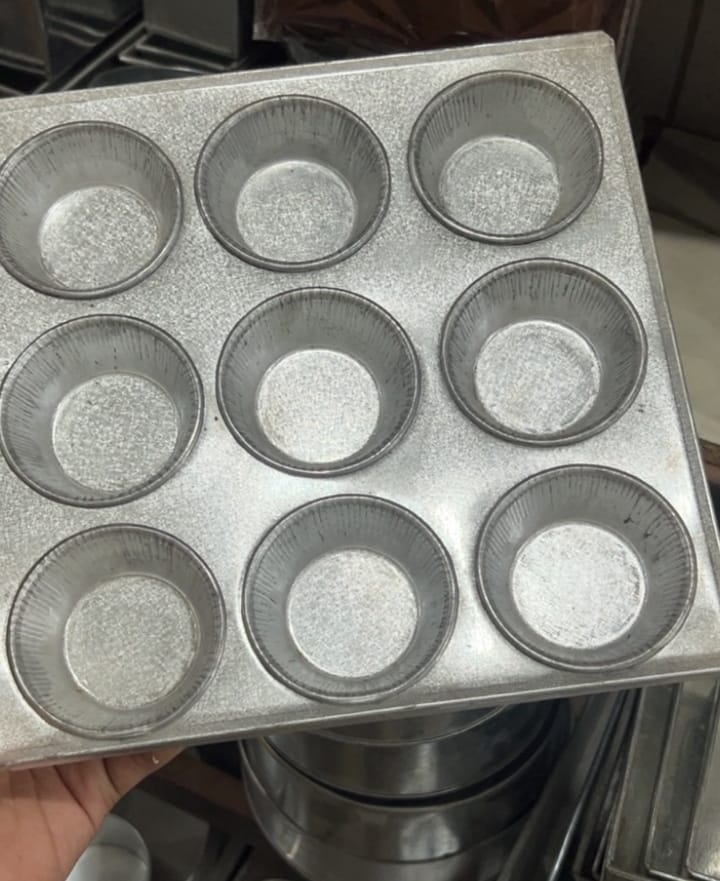 Metal muffin tin with multiple compartments on a kitchen counter.