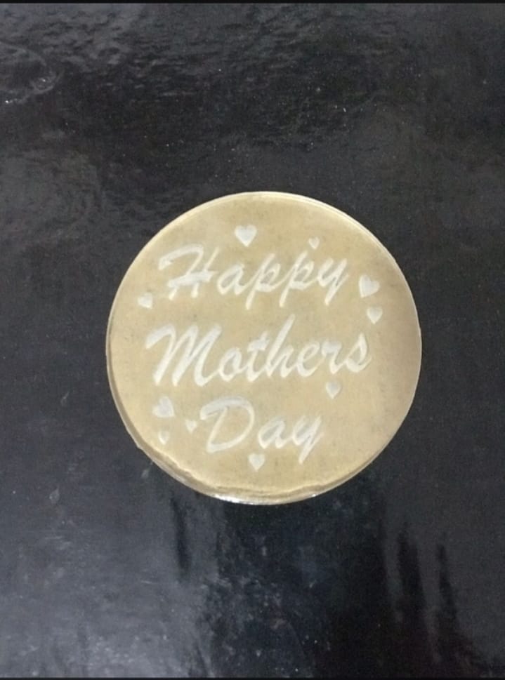 Round gold token with 'Happy Mother's Day' engraving on a dark background