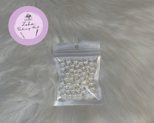Packaged white pearls on a fur surface with a visible brand label.
