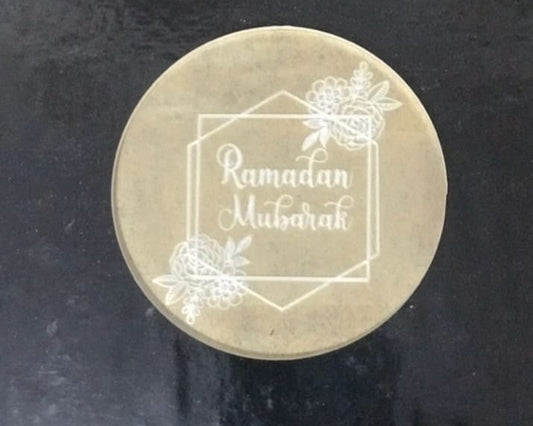 Round metallic object with 'Ramadan Mubarak' engraving on a dark background